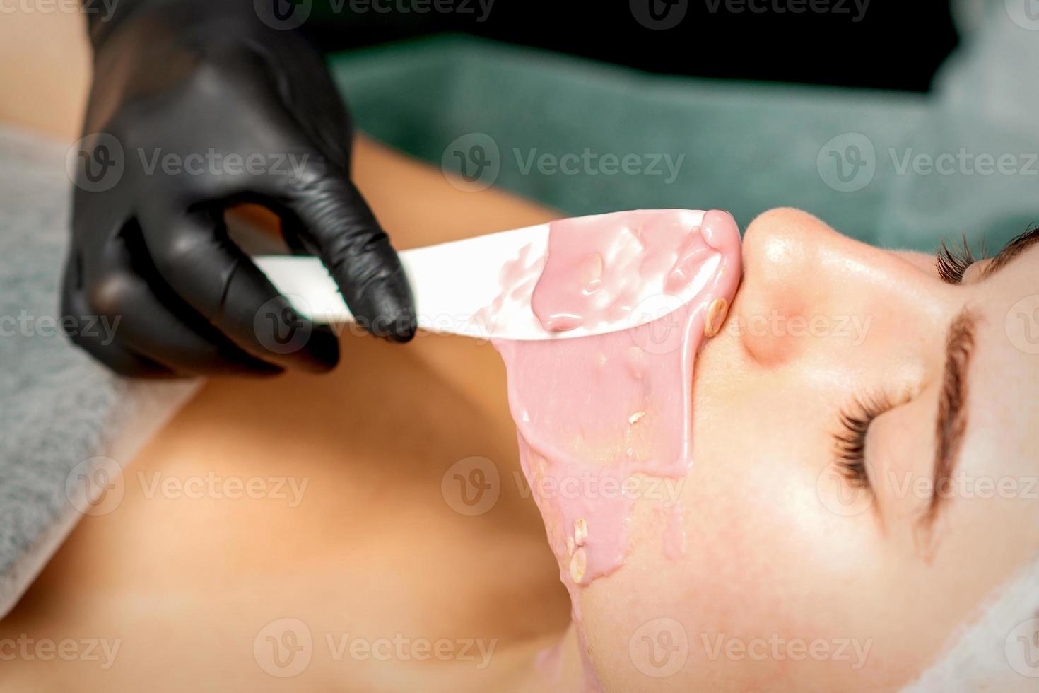Cosmetologist applying an alginic mask photo
