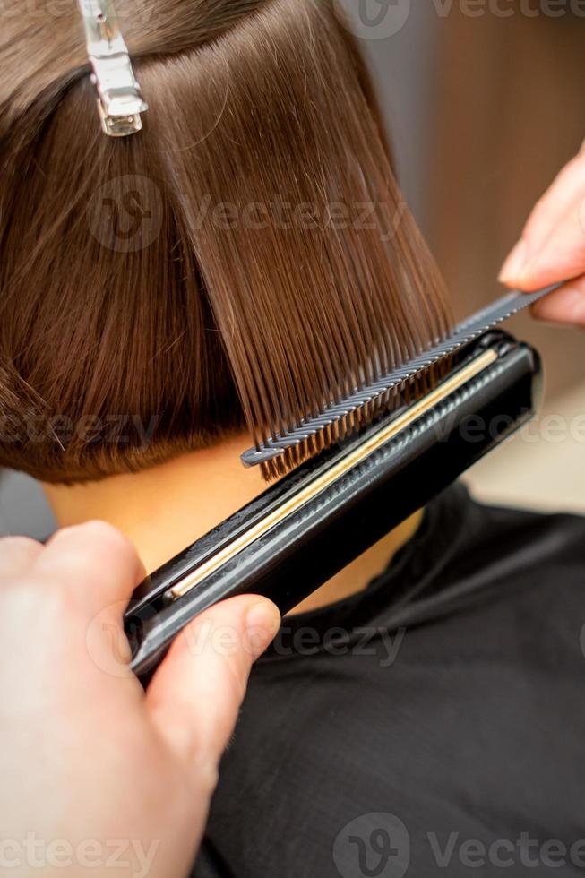 Hairdresser straightening the short hair photo