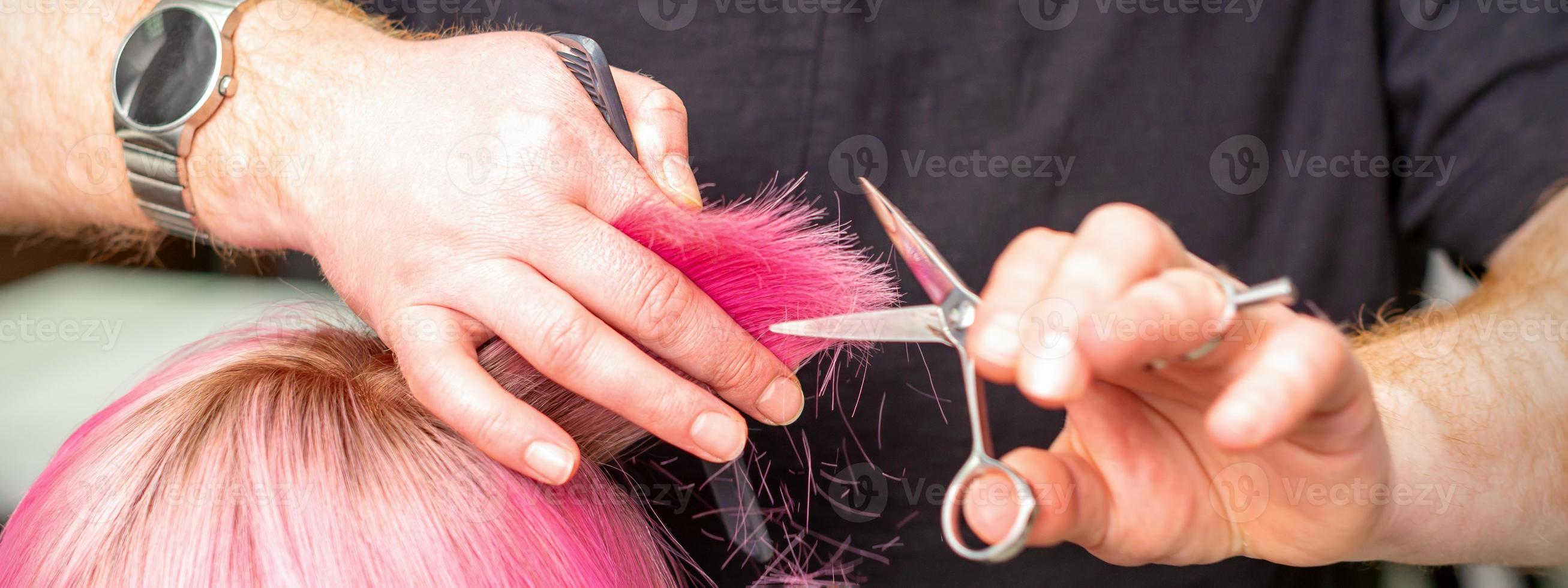 Hairdresser cutting short pink hair photo