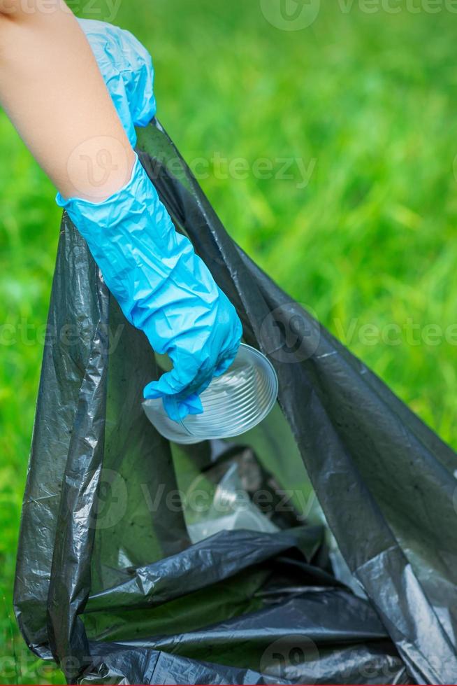 niño pone el plastico en basura bolso foto