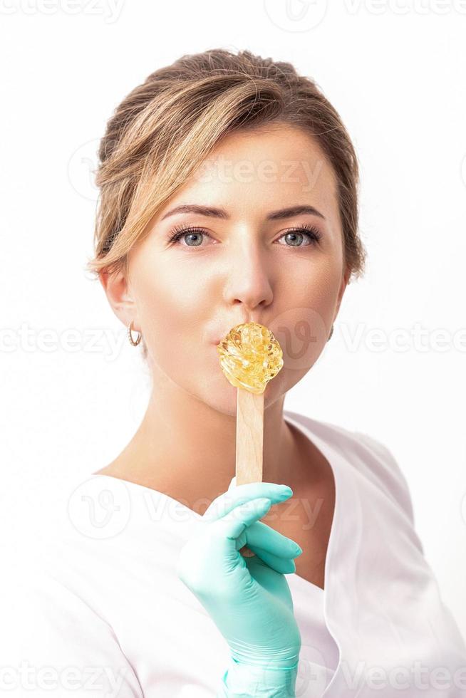 Cosmetologist holds wooden stick with wax photo