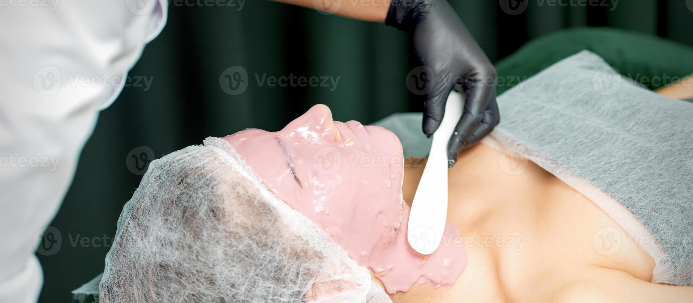 Cosmetologist applying an alginic mask photo