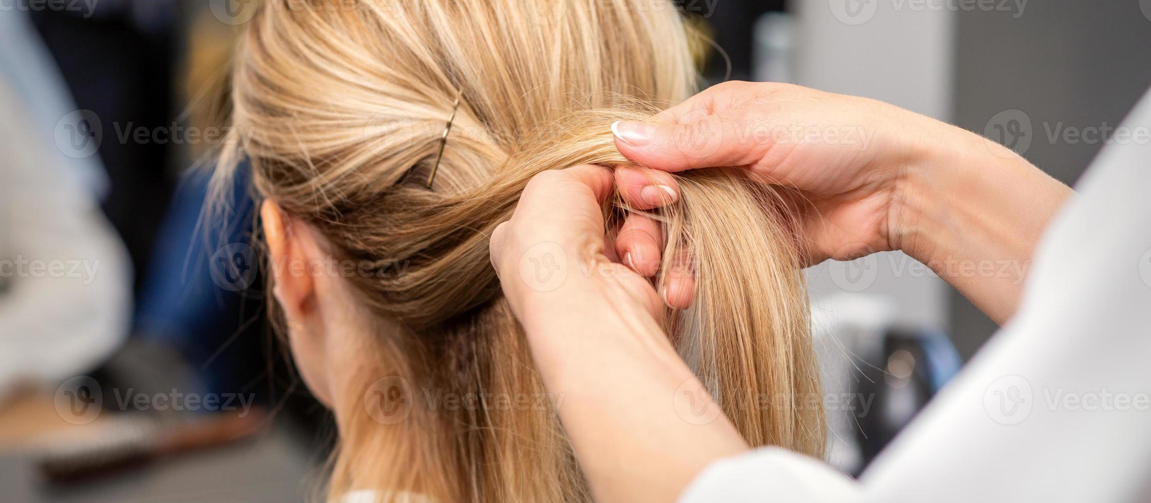 Hairdresser's hands braiding client's hair photo