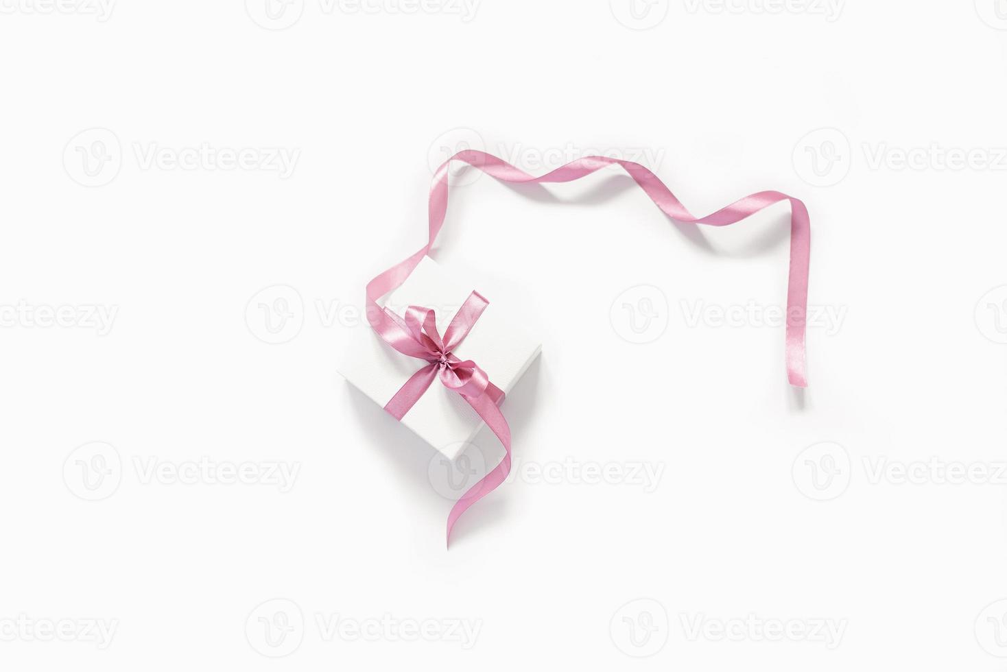 Gift white box with a pink bow satin ribbon on a white background. Birthday greeting card, Wedding, Christmas, March 8, mother's day photo