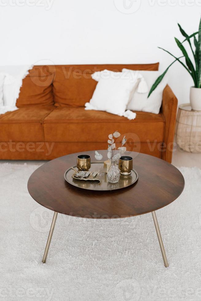 Round coffee table with a tray of glasses, flowers in a vase in the living room in the Scandinavian style photo