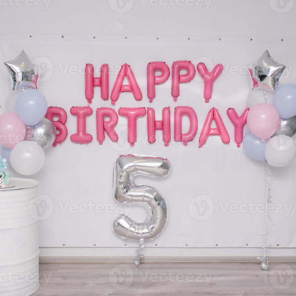 Pink garland of foil balloons happy birthday on the holiday for the 5th anniversary of the child. Photo zone with helium balloons