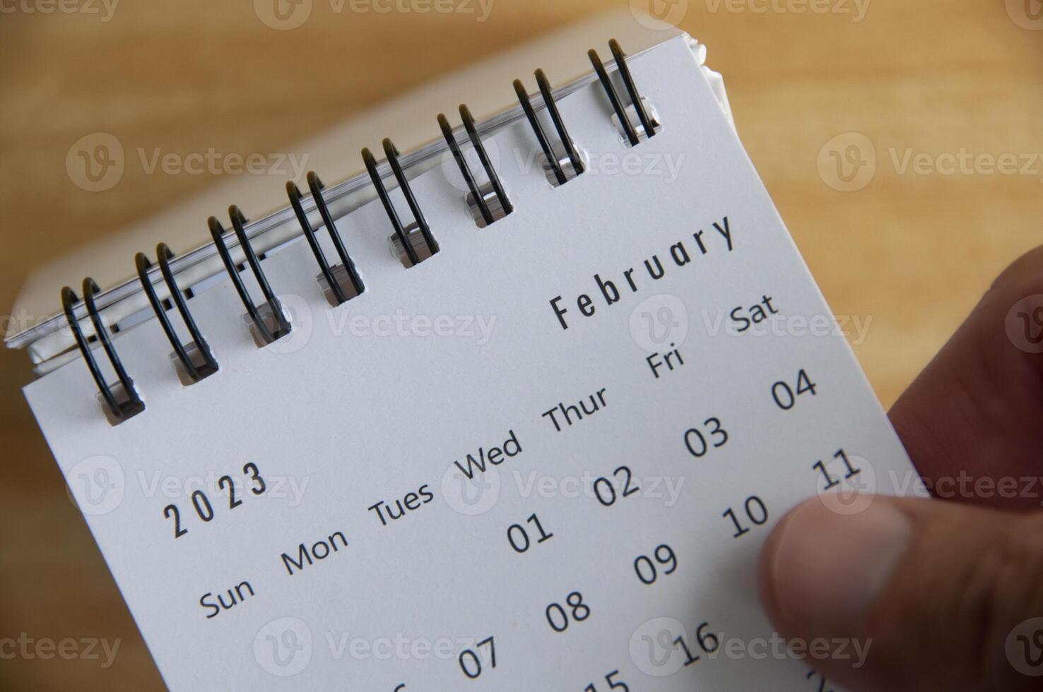 Top view of hand flipping February 2023 calendar. Calendar concept photo