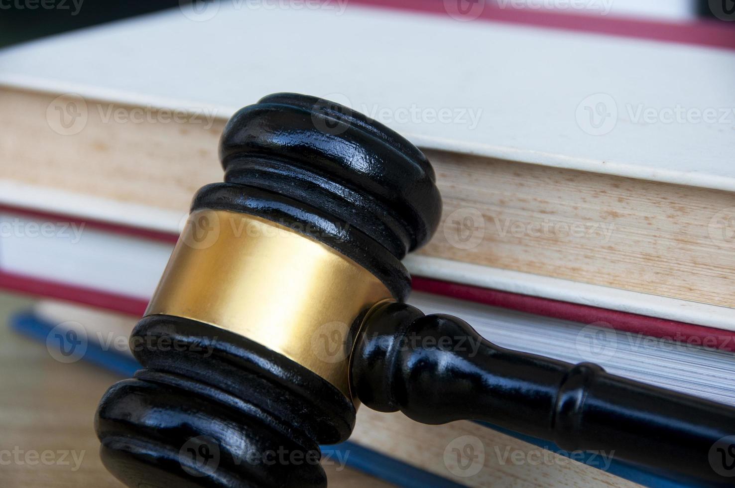 Close up of Lawyer's gavel on wooden table with stack of books background. Copy space and law concept photo