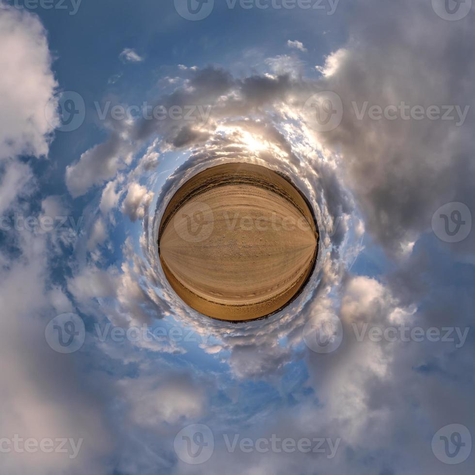 tiny planet in blue overcast evening sky with beautiful clouds with transformation of spherical panorama 360 degrees. Spherical abstract aerial view. Curvature of space. photo