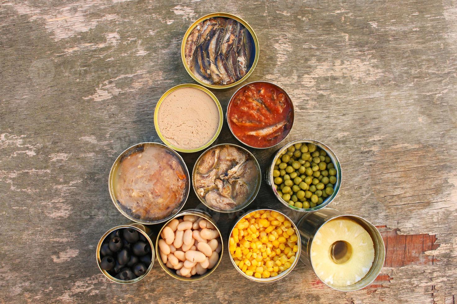 Different open canned food on old wooden background. Top view. Flat lay. photo