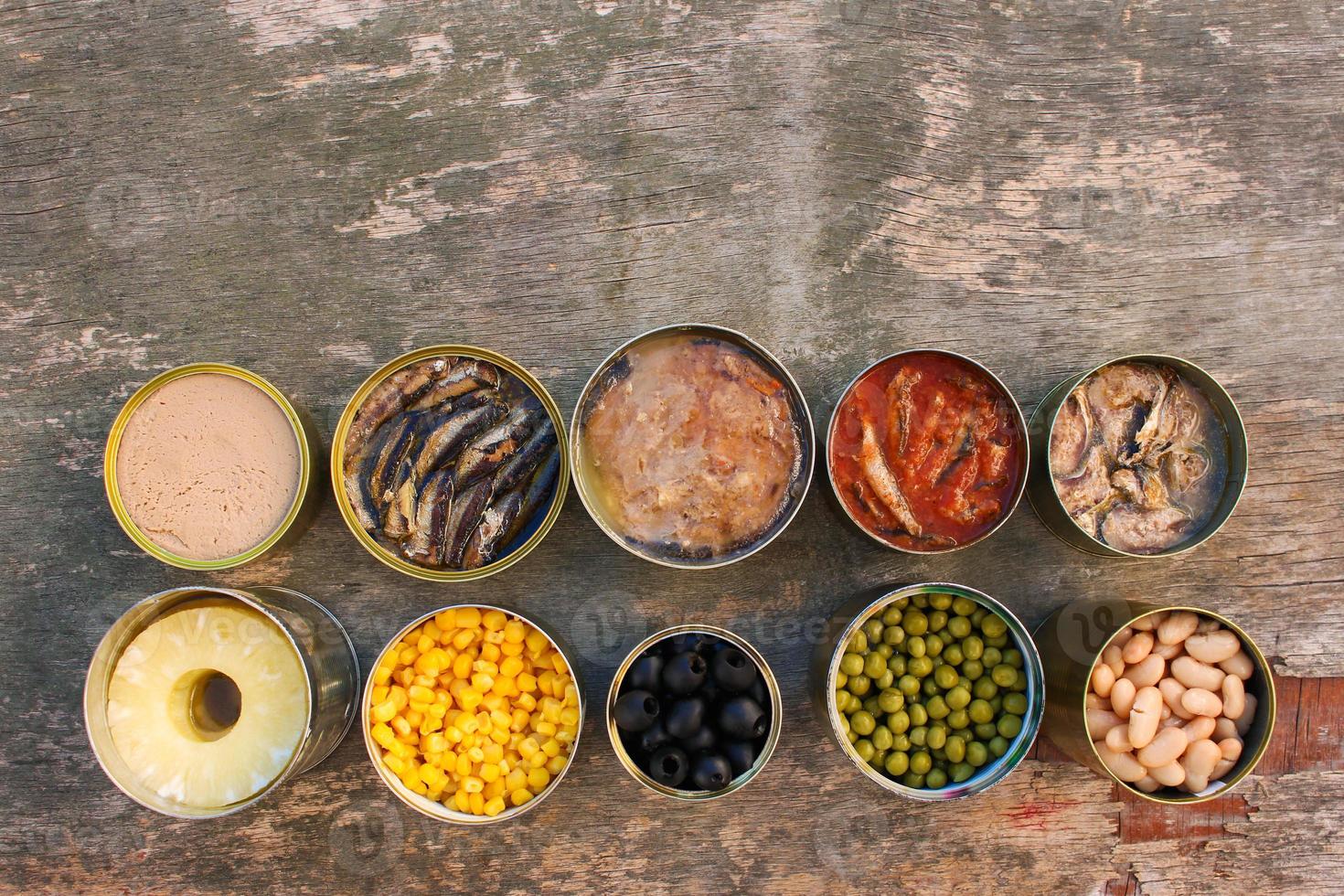 Different open canned food on old wooden background. Top view. Flat lay. photo