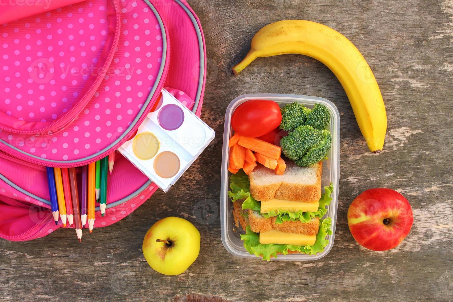 Sandwiches, fruits and vegetables in food box, backpack on old wooden background. Top view. Flat lay. photo