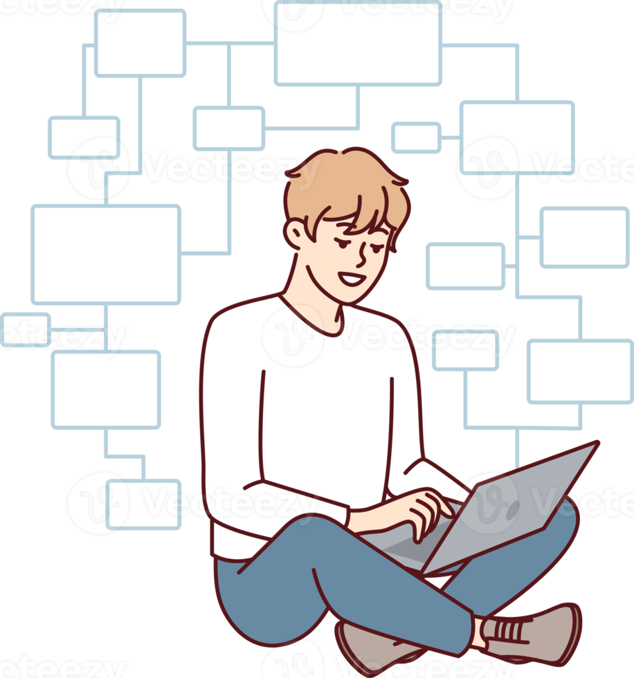 Jeune homme programmeur est assis jambes croisées sur sol avec portable sur tour et crée applications png