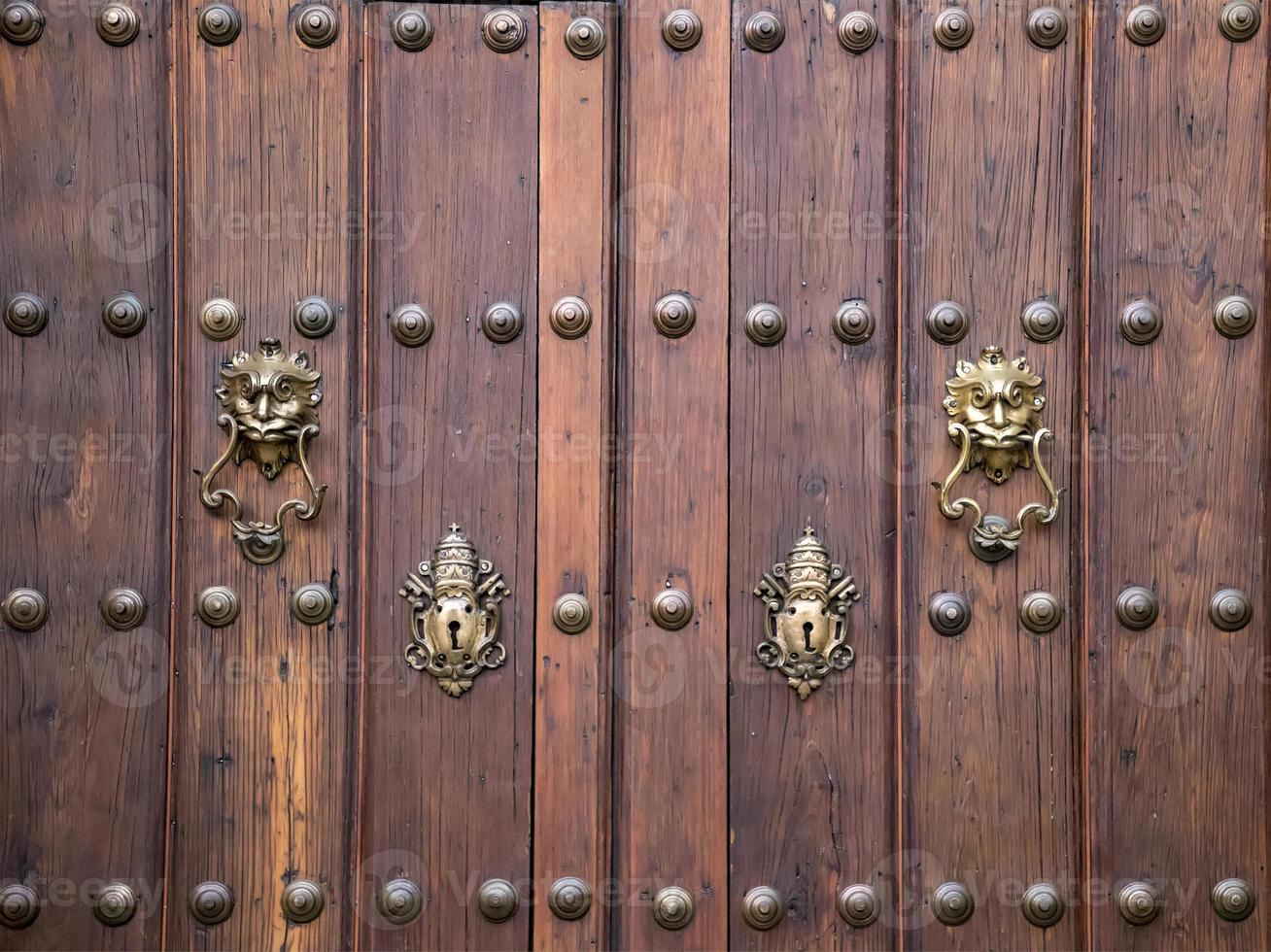 Old vintage wooden door ornate with a beauty metal furniture. Close up photo