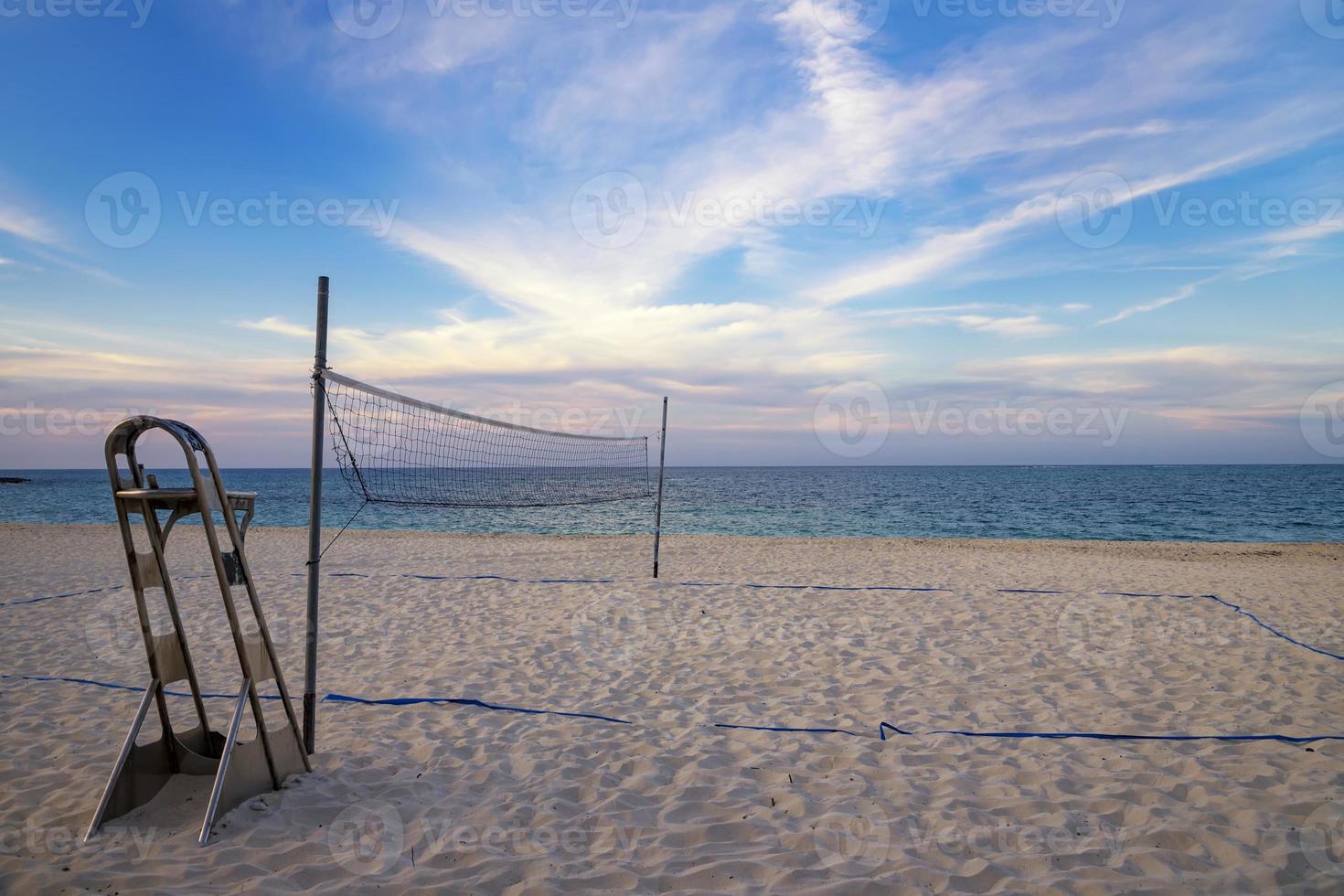 A beach volleyball net on the sandy tropical beach at the sunset or sunrise photo