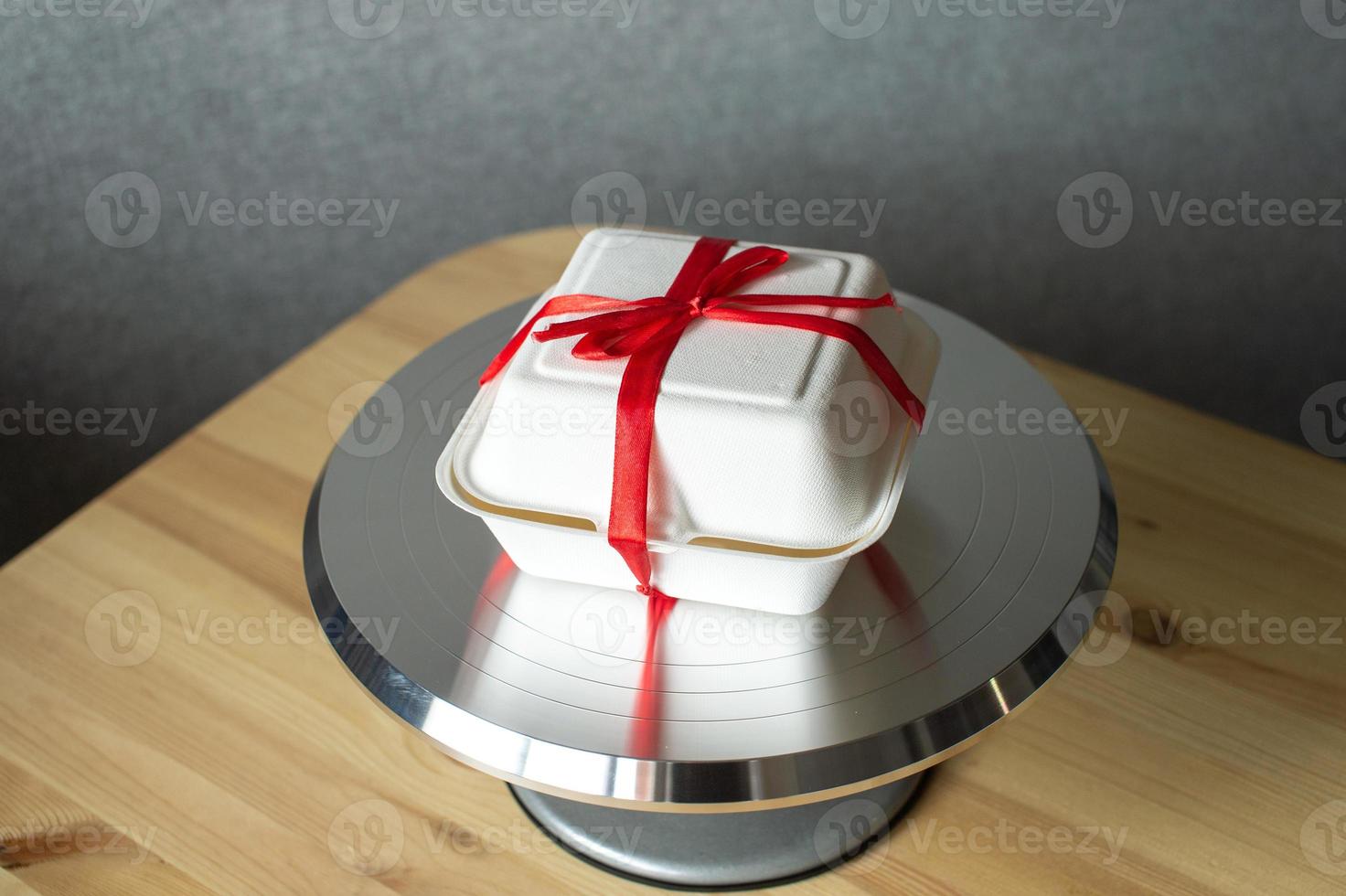 blanco caja con rojo cinta para pastel bento en Pastelería metal placa giratoria para pasteles foto