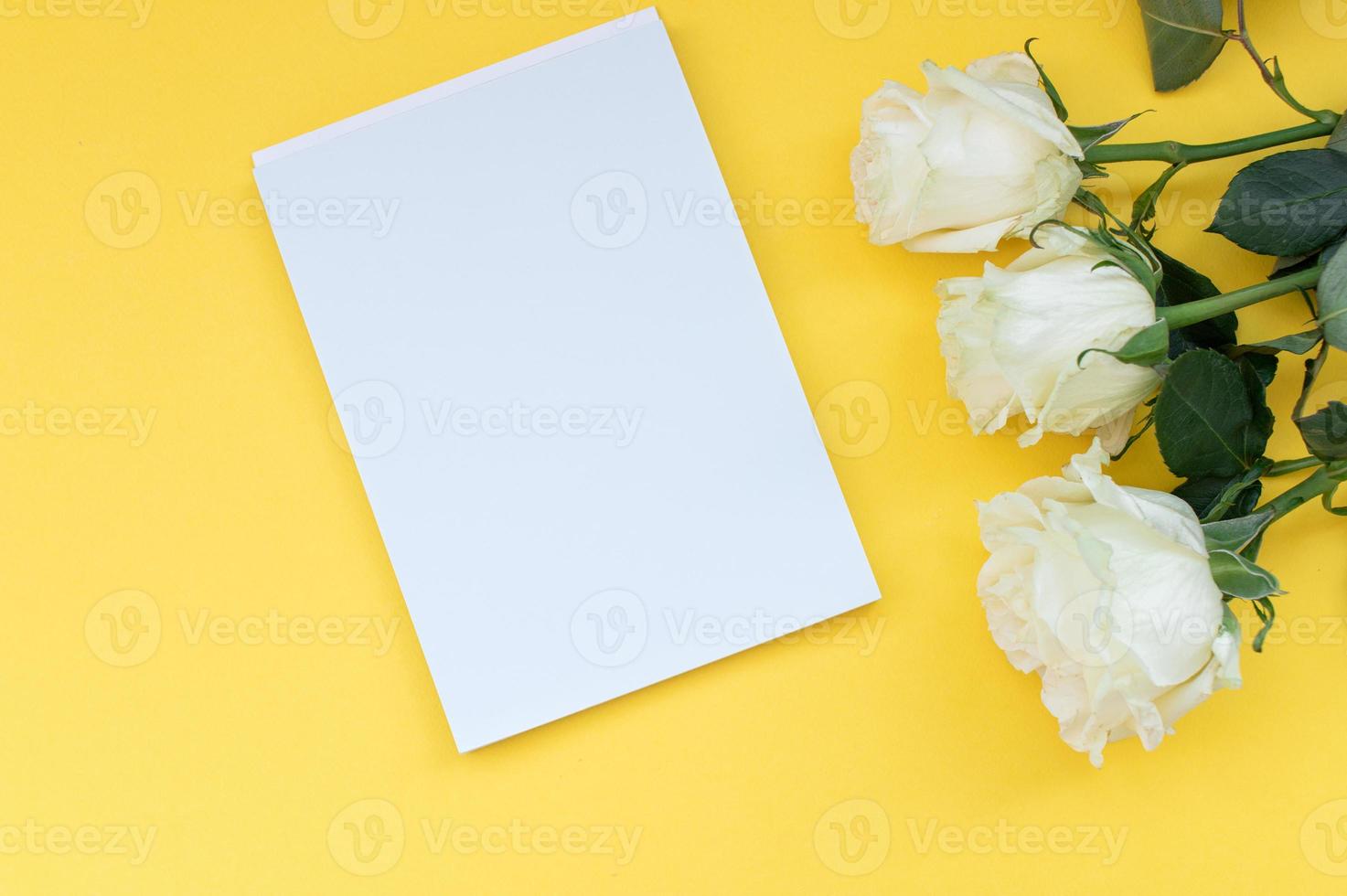 parte superior ver de un amarillo mesa con un Bosquejo de vacío cuadernos con un ramo de flores de rosas. sitio para texto foto