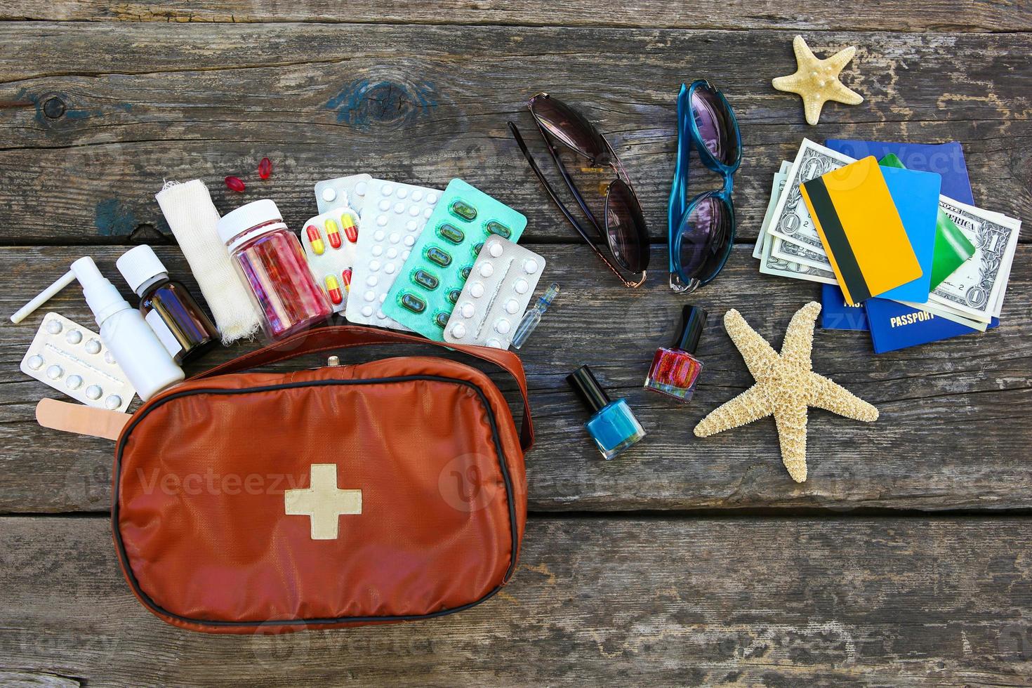 Summer women's beach accessories for your sea holiday and first aid kit on old wooden background. Concept of medication required in journey. Top view. Flat lay. photo