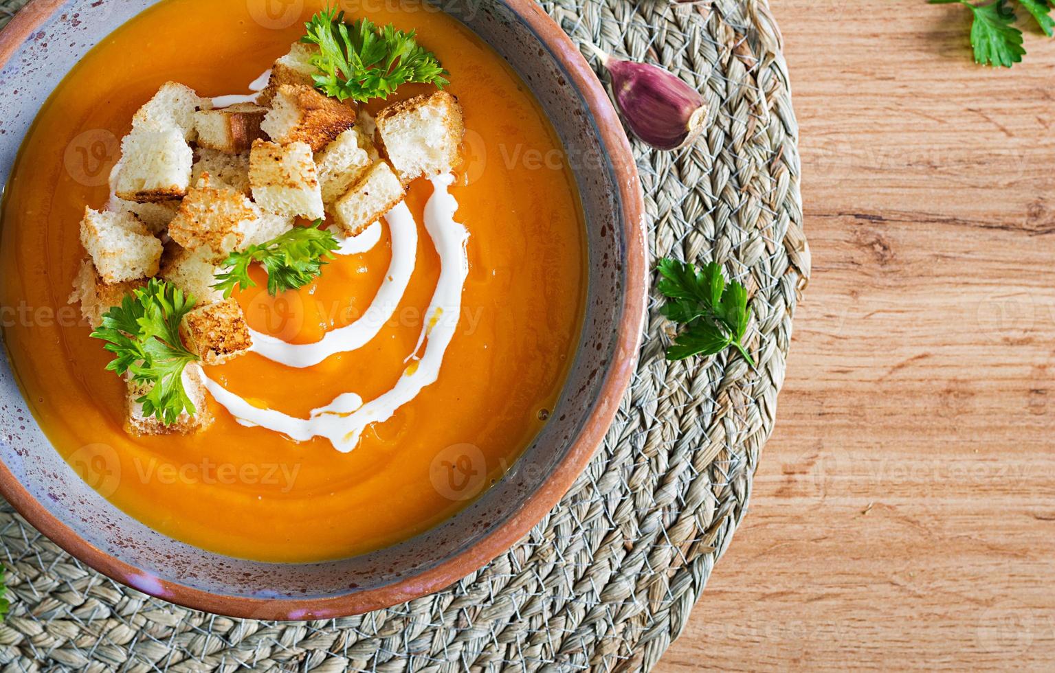 Pumpkin soup in a bowl served with parsley and croutons. Vegan soup. Thanksgiving day food. Halloween meal. Top view photo