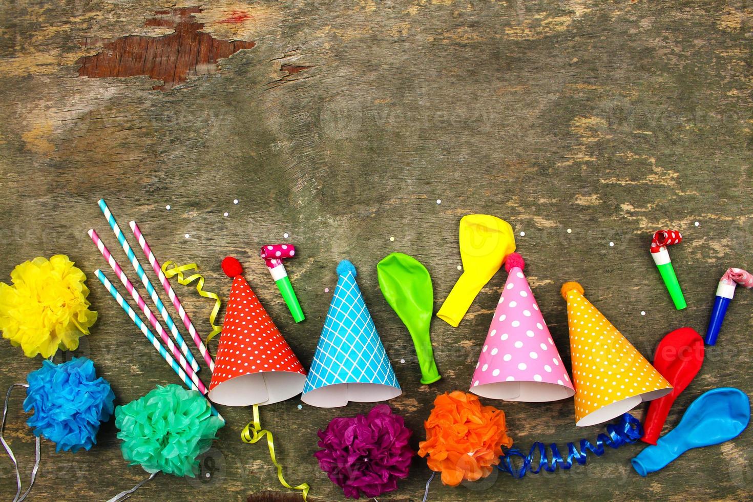 Holiday hats, whistles, balloons on old wooden background. Concept of children's birthday party. Top view. photo