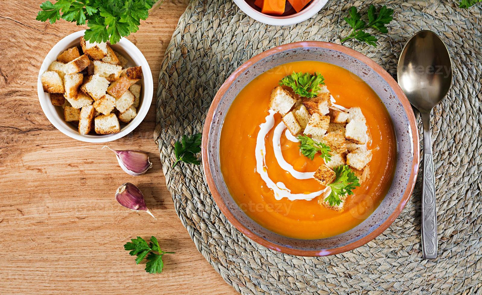 Pumpkin soup in a bowl served with parsley and croutons. Vegan soup. Thanksgiving day food. Halloween meal. Top view photo