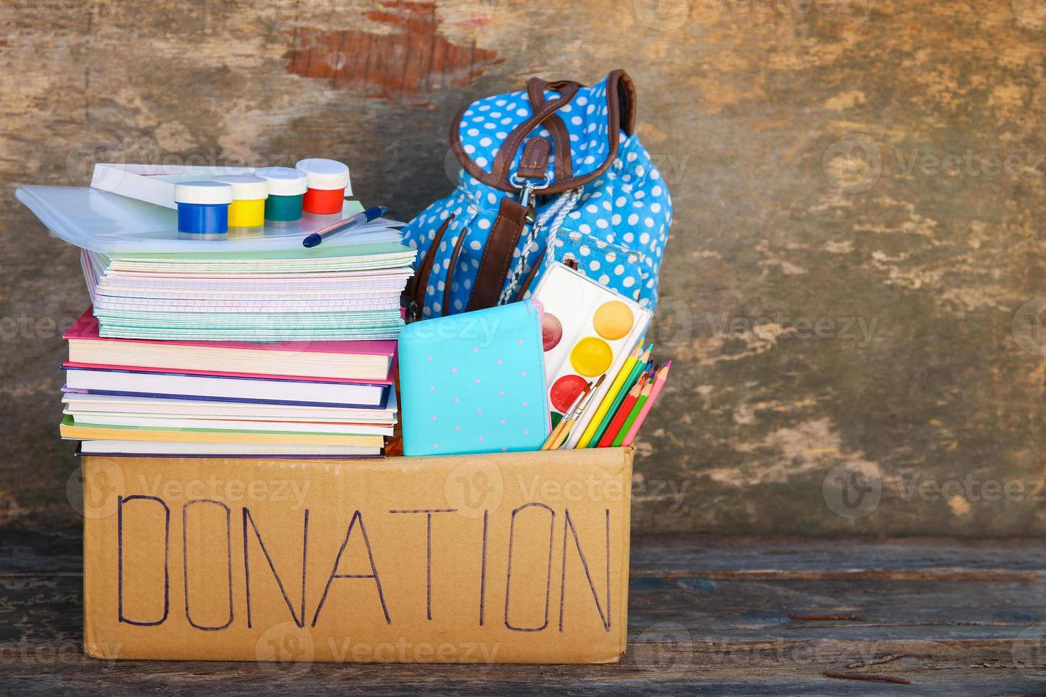 Donation box with school supplies on old wooden background. photo