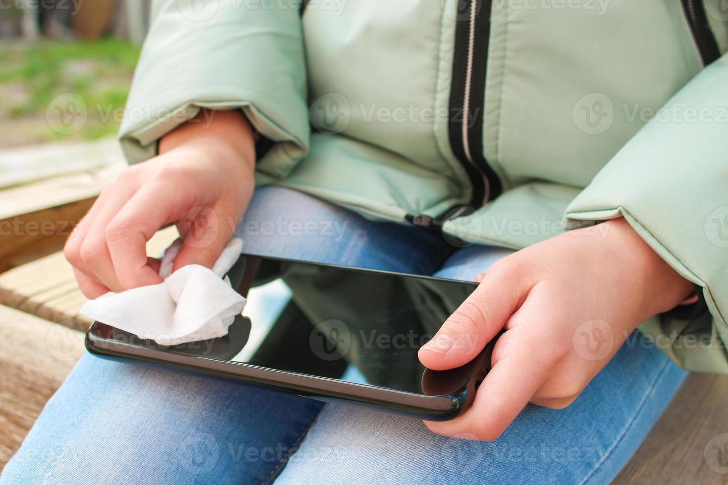 Person cleans mobile phone with wet wipes. photo