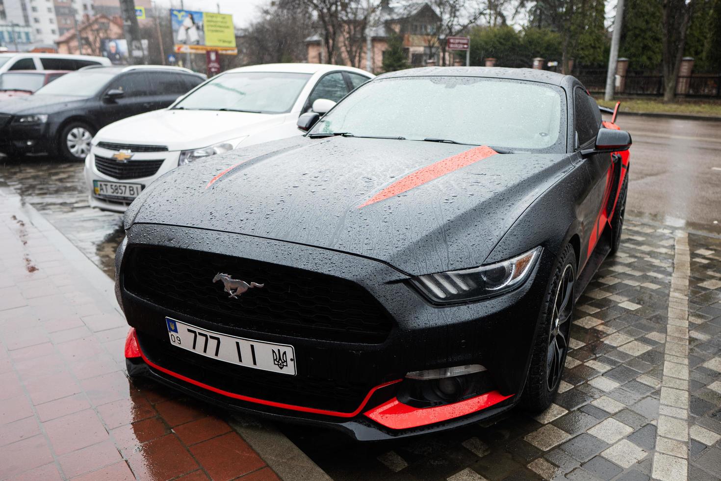 Black and red Ford Mustang with 777 license plates on street. photo