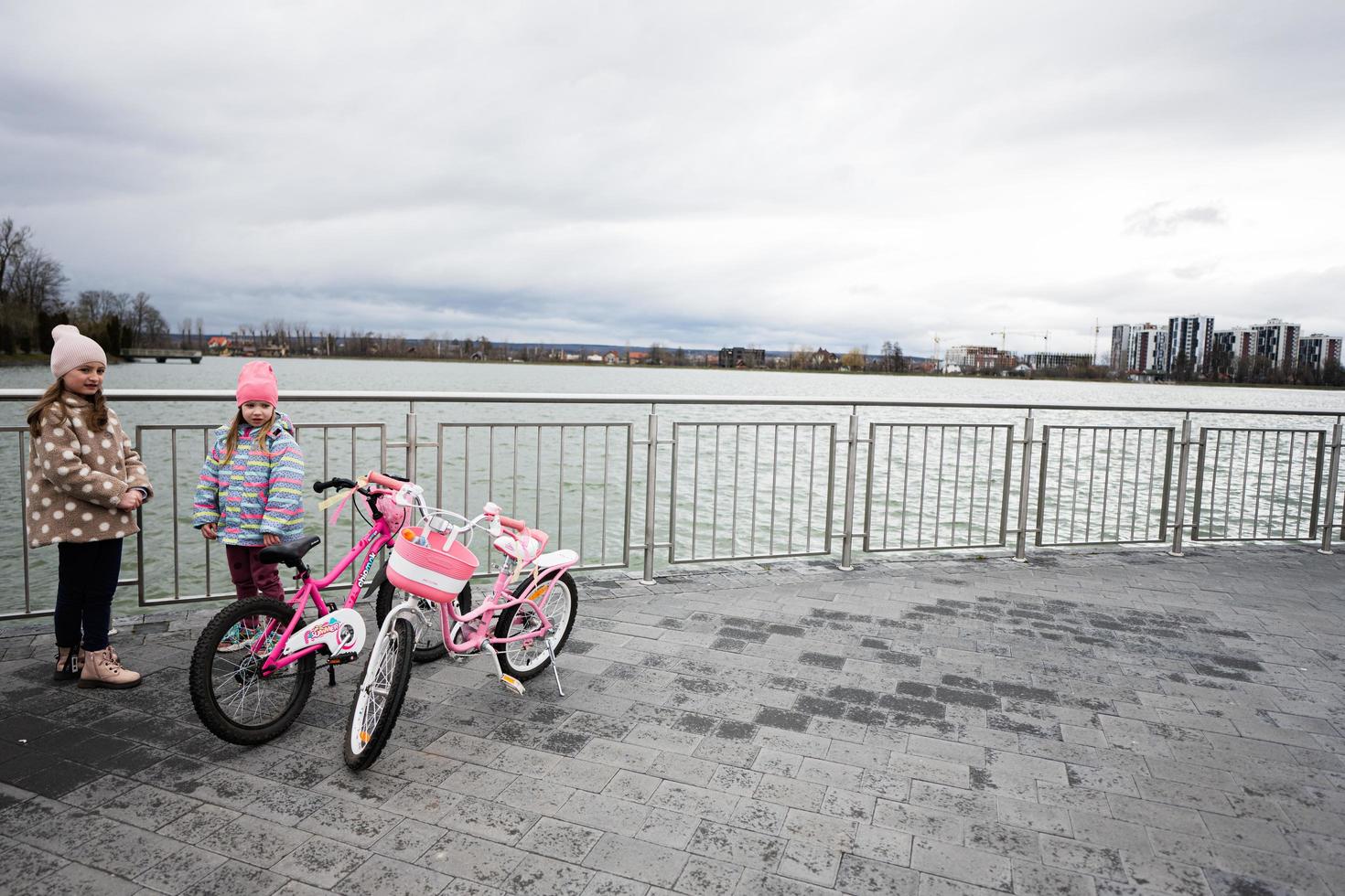 muchachas con rosado Rosa bicicleta cerca lago. foto