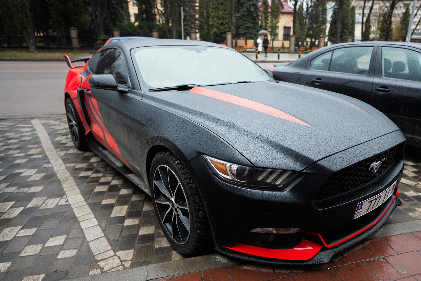 Black and red Ford Mustang with 777 license plates on street. photo