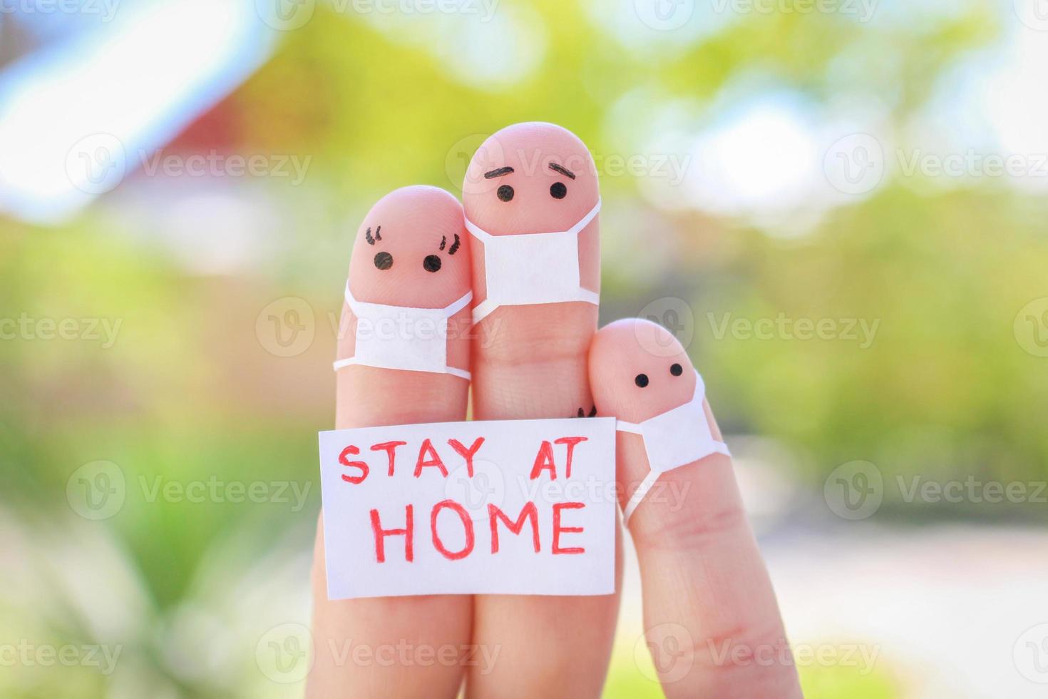 Fingers art of family with face mask is sitting in quarantine at home. People hold placard stay at home to protect yourself from COVID-2019. photo