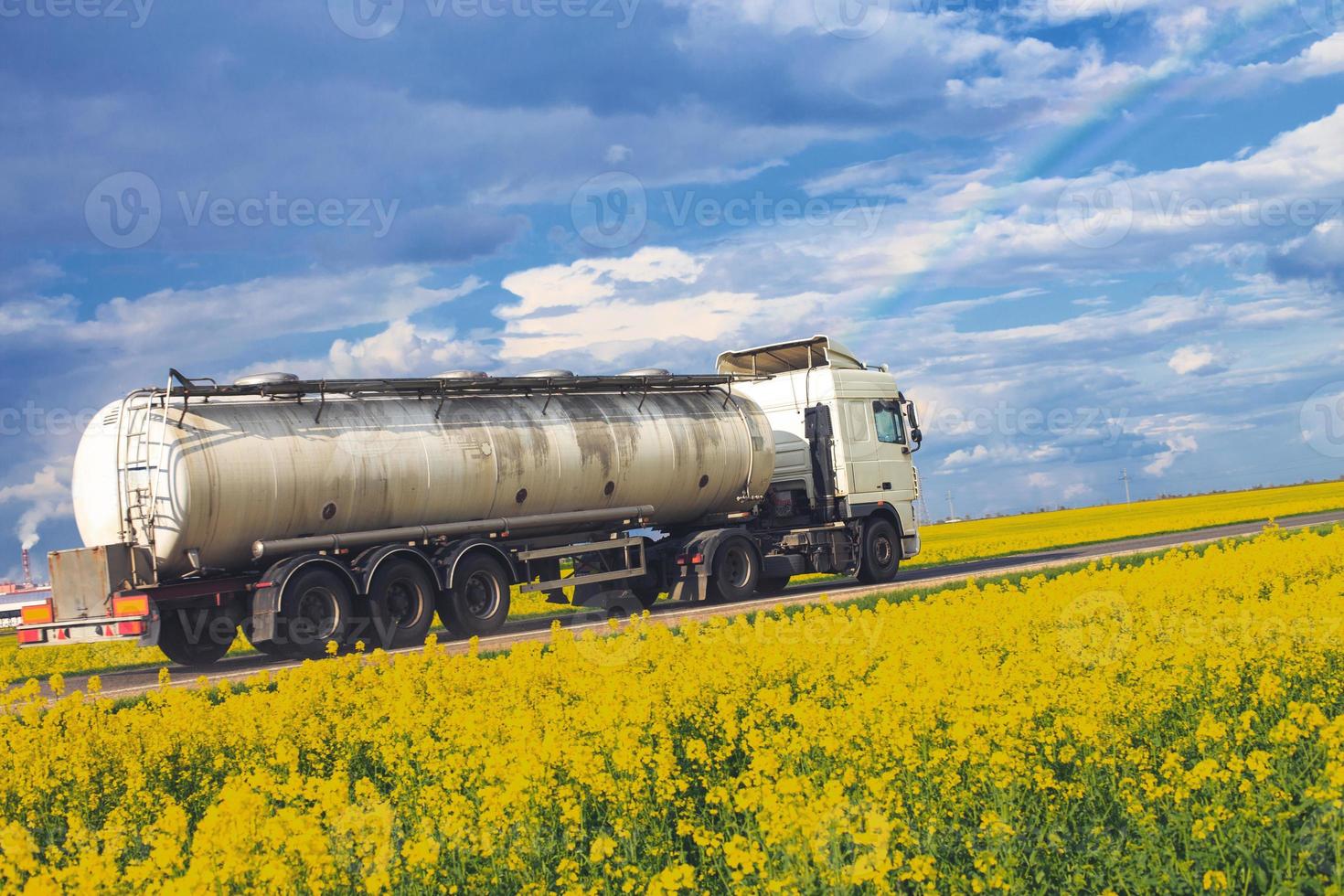 tank goes on the road. truck rides near the field. rainbow in the blue sky photo