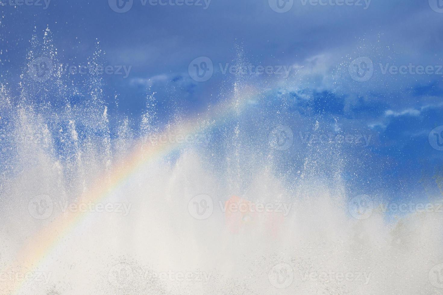 fountain with a rainbow against the blue sky photo