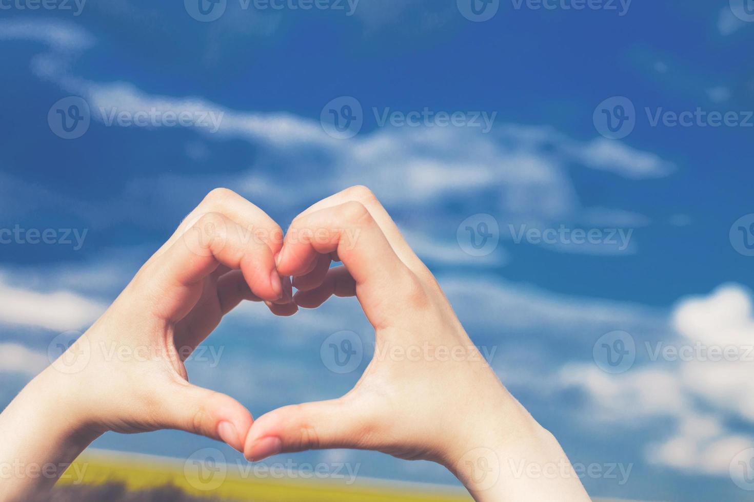 niño corazón desde manos en un antecedentes de azul cielo foto