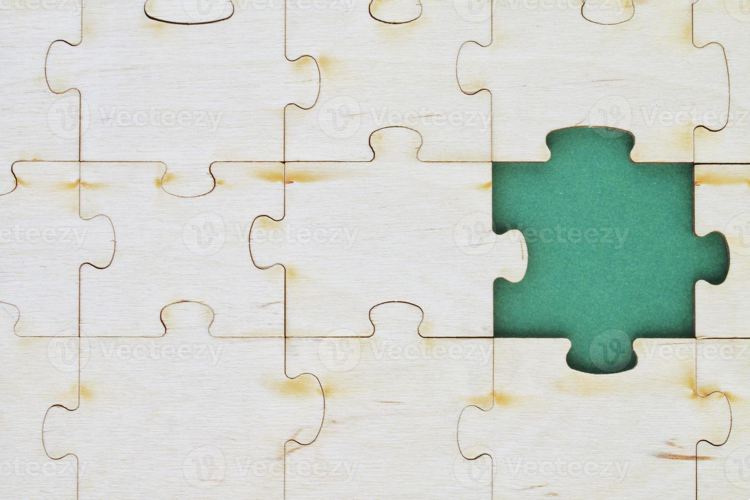 Incomplete and absence wooden puzzle piece with green backdrop. Missing piece. Mental health concept. Symbol of problem solving. Business creative solution. Communication idea. Hobby, play, fun game photo