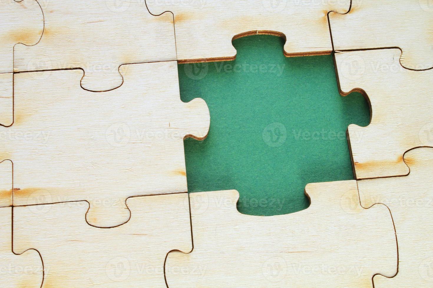 Incomplete and absence wooden puzzle piece with green backdrop. Missing piece. Mental health concept. Symbol of problem solving. Business creative solution. Communication idea. Hobby, play, fun game photo