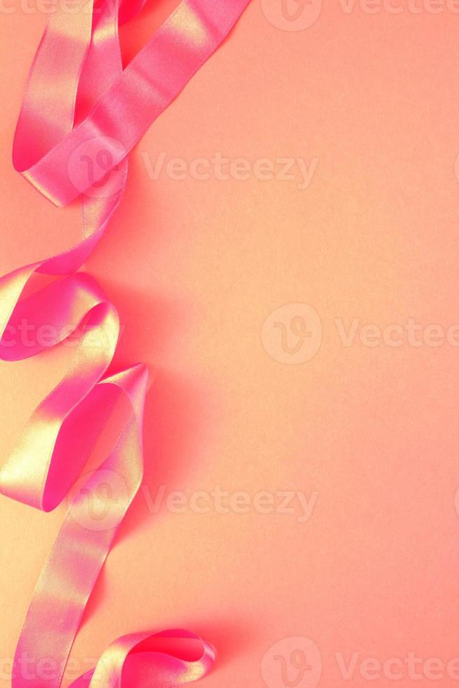 curvo ondulado seda satín rosado cinta en rosado antecedentes con Copiar espacio para texto. día festivo, celebracion, aniversario, cumpleaños regalo decoración concepto. idea para saludo tarjeta, rebaja bandera foto