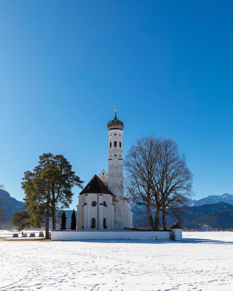 Church in the snow with a muntains and a blue sky photo