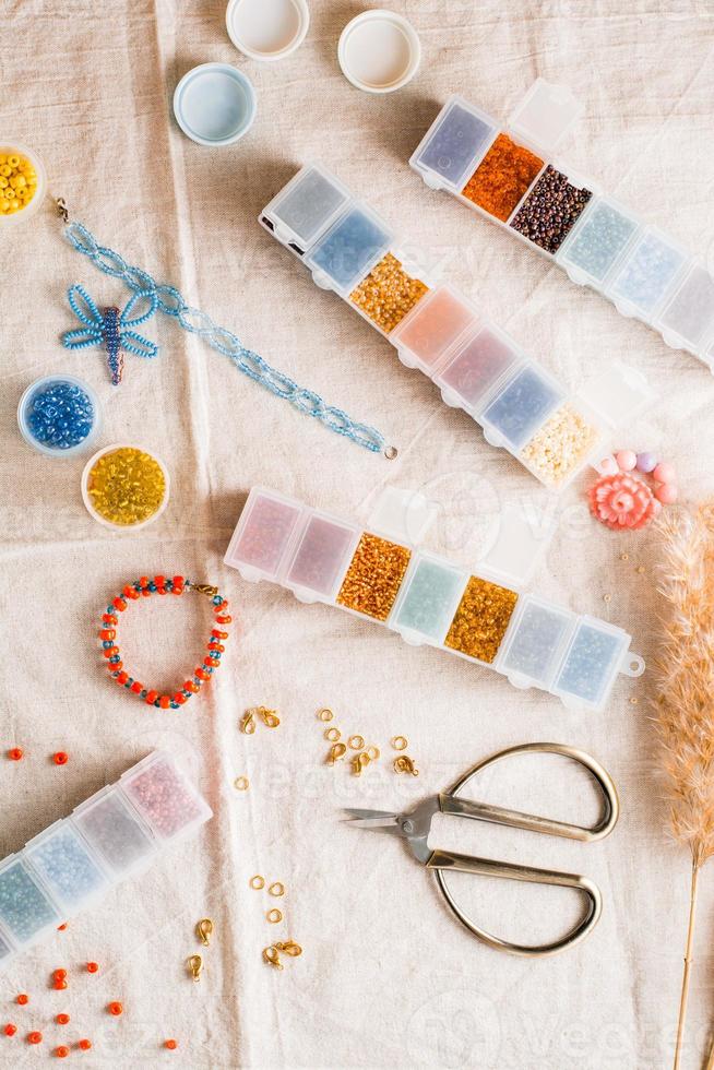 Items for beading - boxes with beads, thread and scissors on the table. Development of creative skills and fine motor skills for children. Top and vertical view. photo