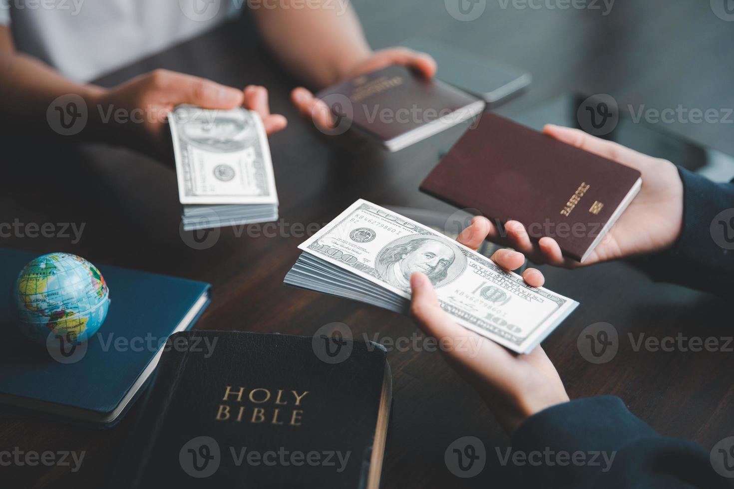 Concept of Christian ministry. Small groups pray together for Christian mission. Mission to spread gospel and religion of Christianity around world. Hands holding dollar and passport on wooden table. photo