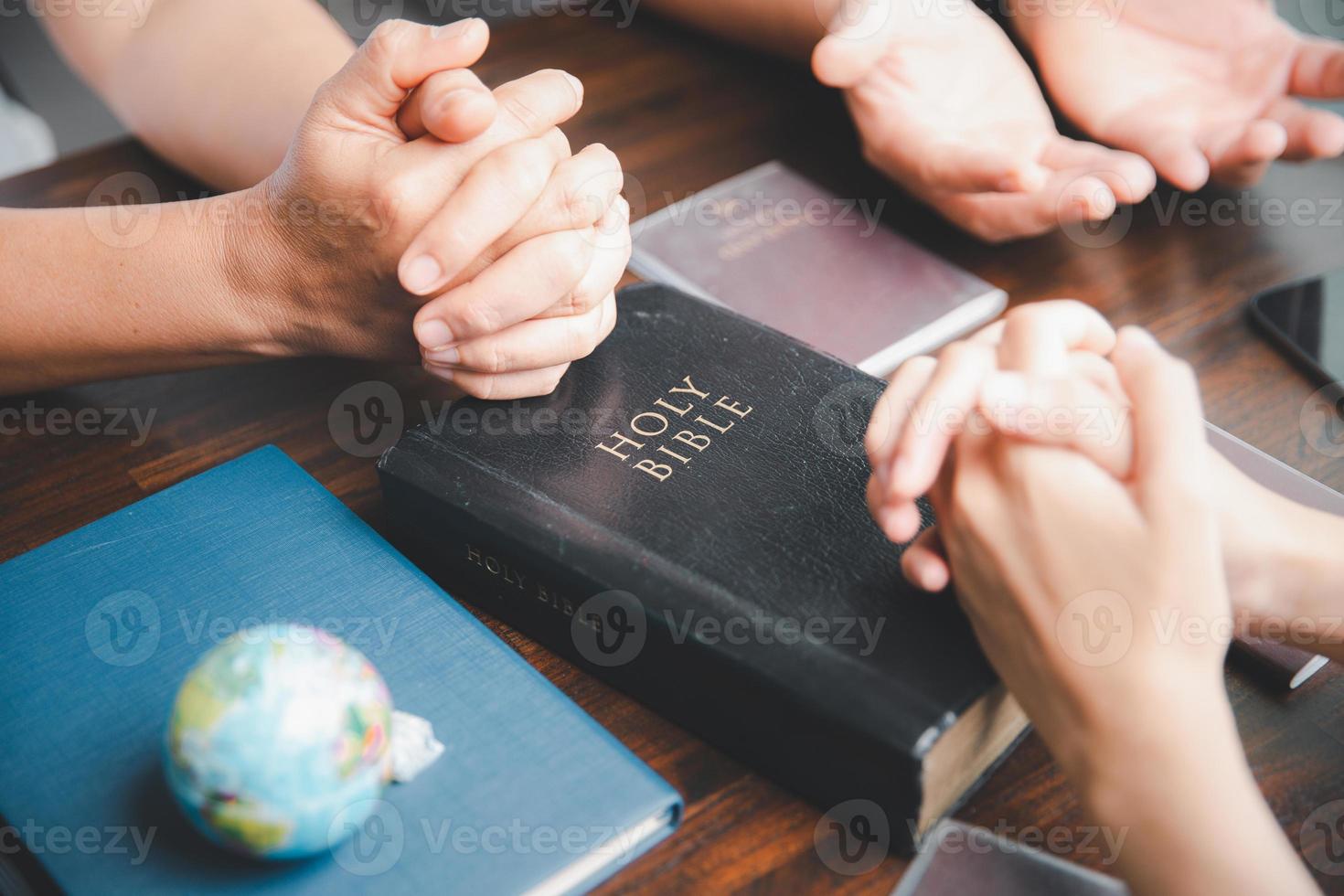 Concept of Christian ministry. Small groups pray together for Christian mission. Mission to spread the gospel and religion of Christianity around the world. hands praying with bible on wooden table. photo