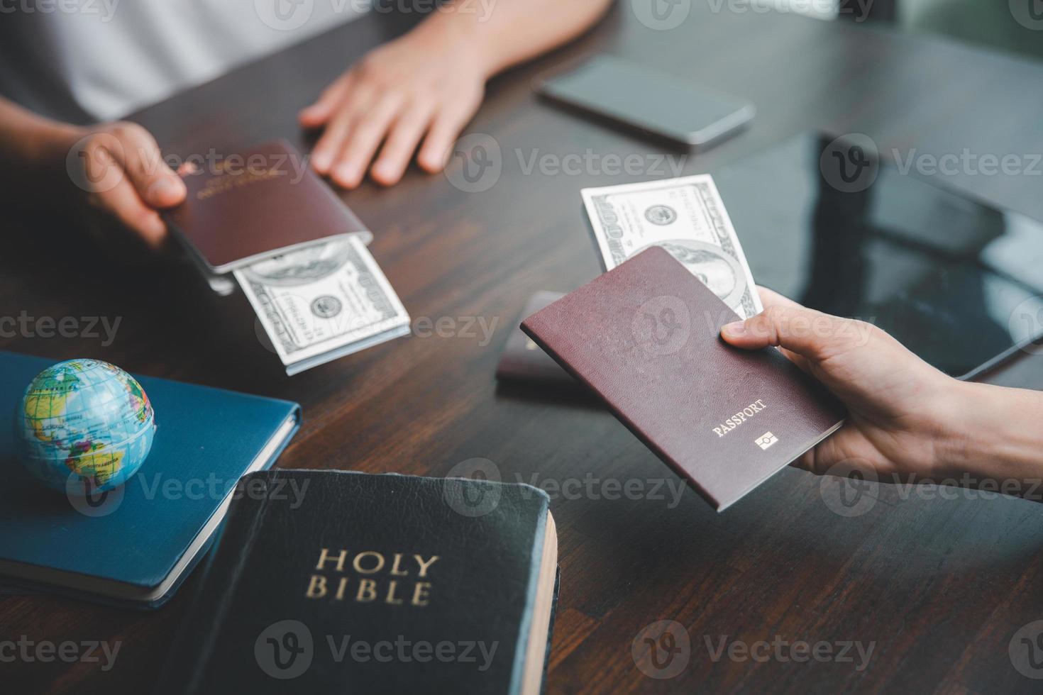 Concept of Christian ministry. Small groups pray together for Christian mission. Mission to spread gospel and religion of Christianity around world. Hands holding dollar and passport on wooden table. photo