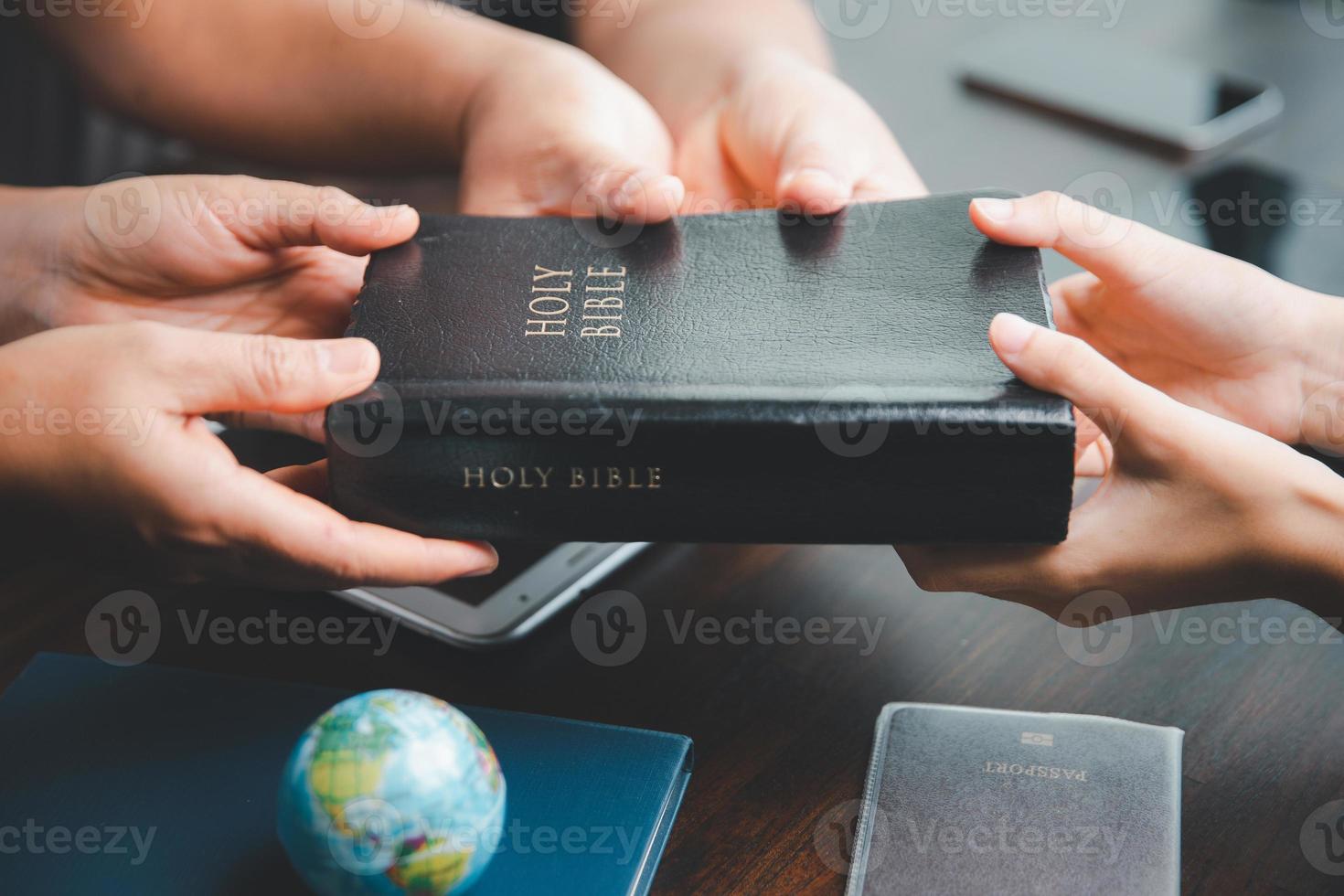 concepto de cristiano ministerio. pequeño grupos orar juntos para el cristiano misión. misión a untado el evangelio y religión de cristiandad alrededor el mundo. manos participación Biblia en de madera mesa. foto