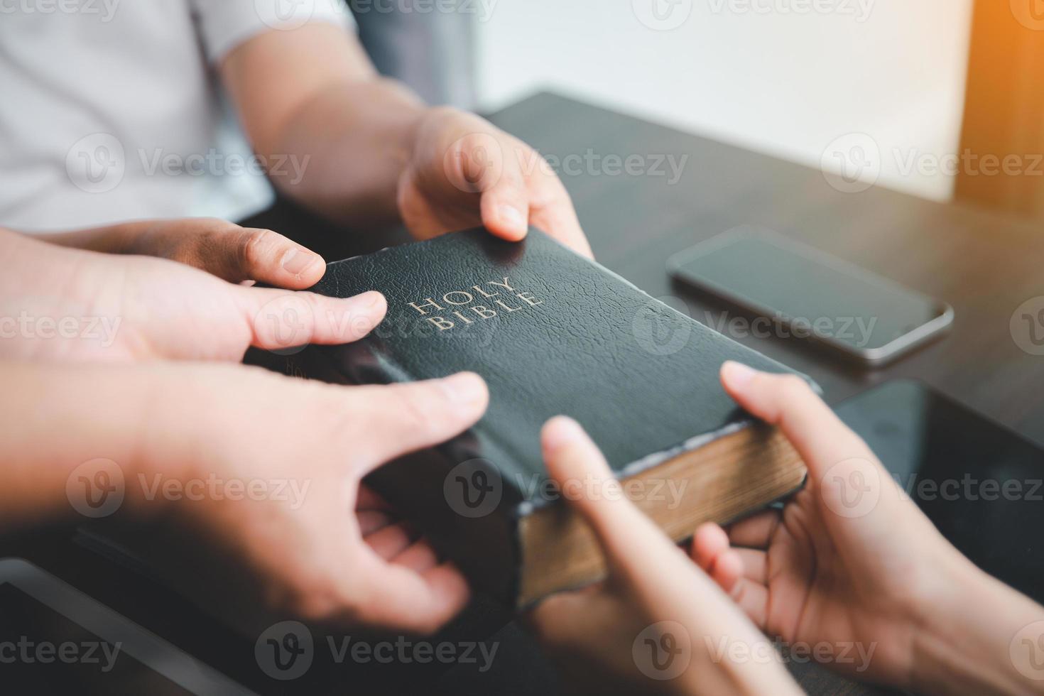 Concept of Christian ministry. Small groups pray together for the Christian mission. Mission to spread the gospel and religion of Christianity around the world. hands holding bible on wooden table. photo