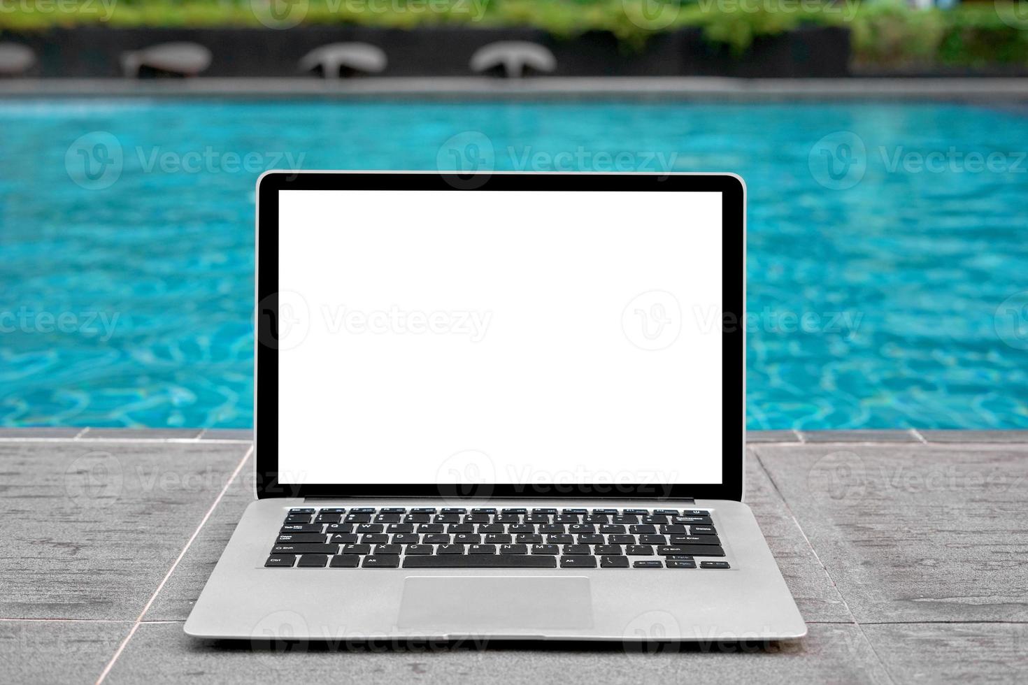 ordenador portátil con blanco pantalla para creativo diseño en piso cerca nadando piscina borde antecedentes. computadora cuaderno con monitor recorte camino para presente aterrizaje página diseño. ordenador portátil computadora burlarse de arriba modelo foto