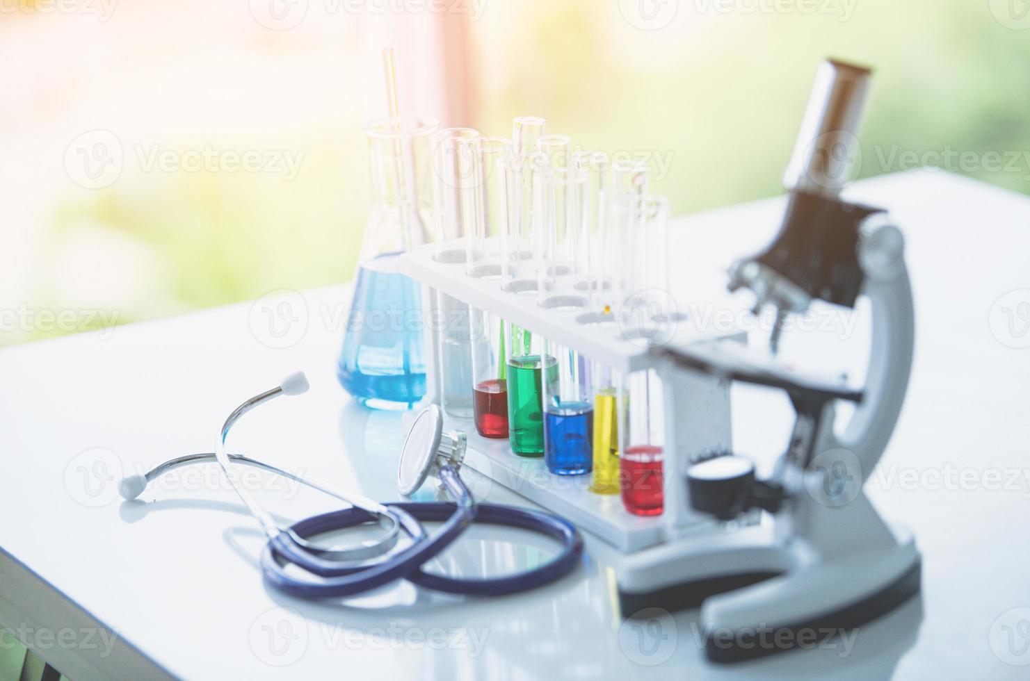 Microscope and colorful test tubes on table in Laboratory. Science chemistry concept. Blue tone photo