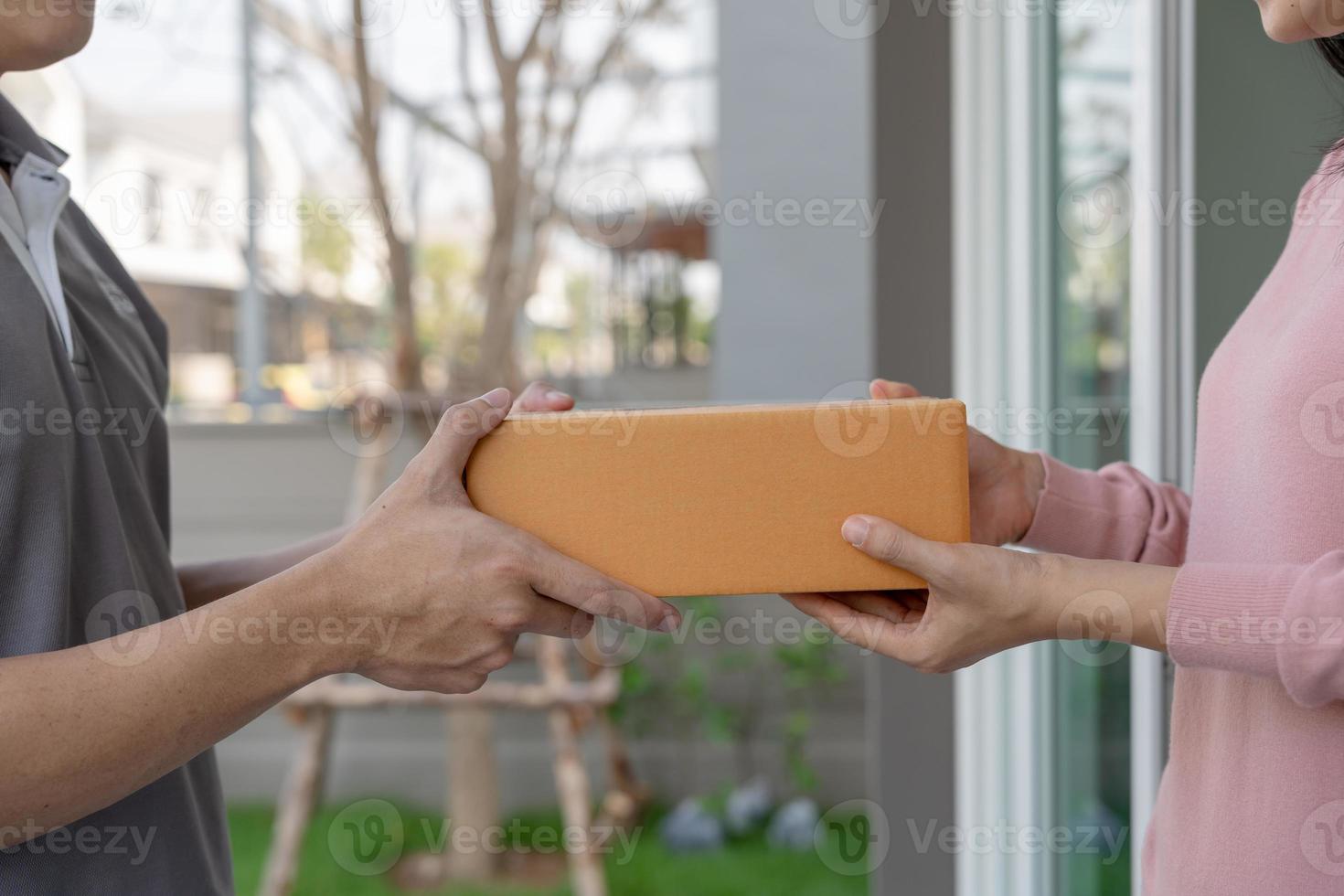 Happy smiling woman receives boxes parcel from courier in front house. Delivery man send deliver express. online shopping, paper containers, takeaway, postman, delivery service, packages photo