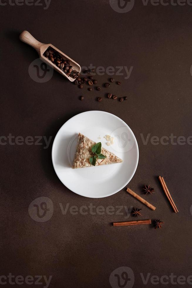 Top view of Layered Cake with cream Napoleon with mint on Brown background. A cinnamon stick, badyan, coffee beans on a brown background. Copy space photo
