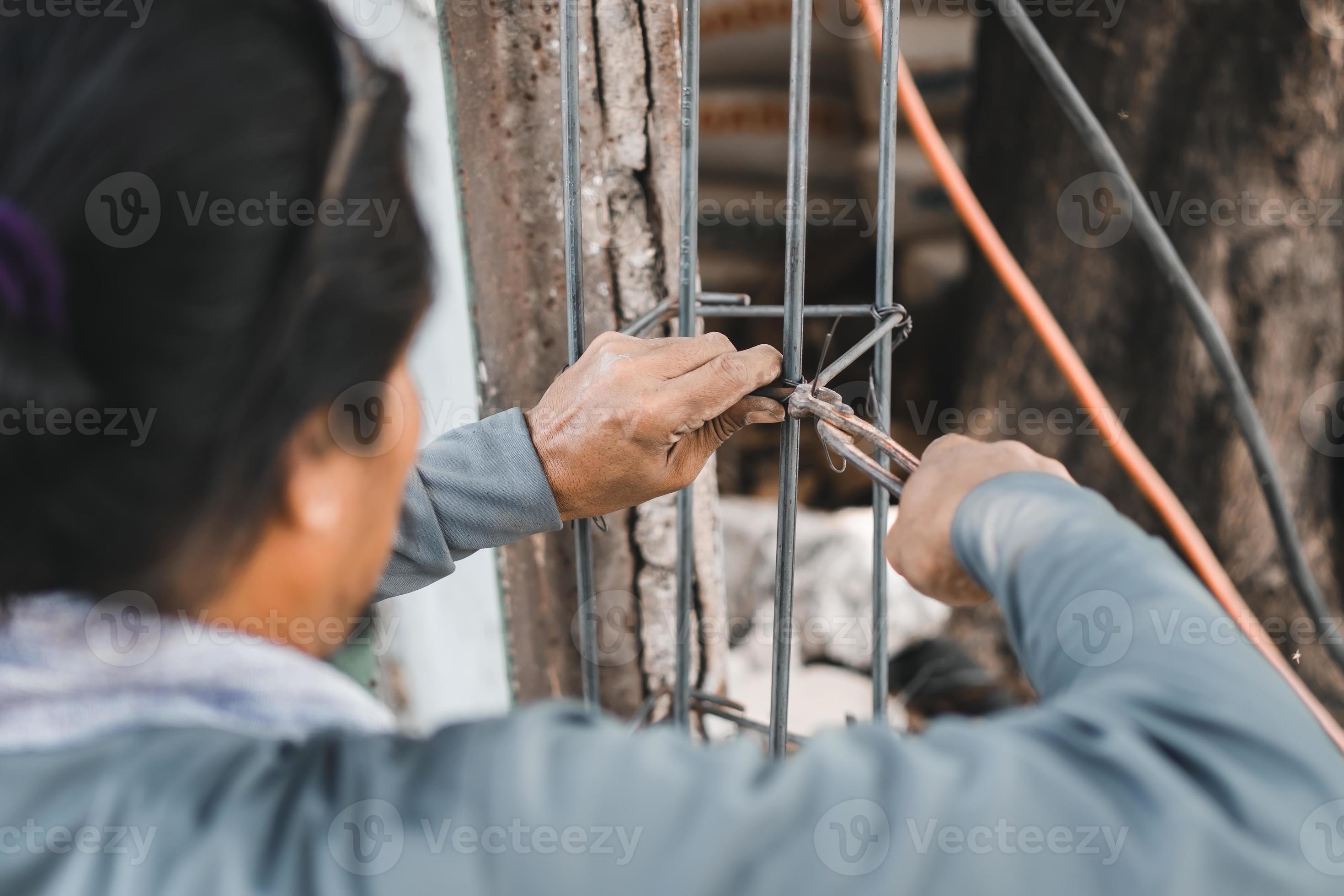 construction workers using wire cutter pliers and steel wire to binding