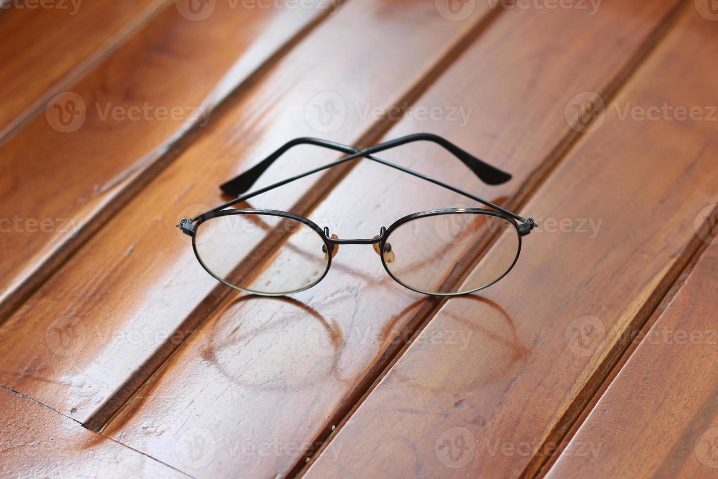 a close up of eyeglasses with black frames isolated natural patterned wooden background. photo